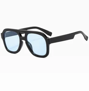 Détail de lunettes de soleil tendance à monture épaisse noire et double pont aux verres bleus.
