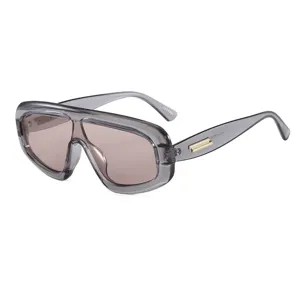 Occhiali da sole oversize alla moda con montatura grigia trasparente e dettagli dorati.