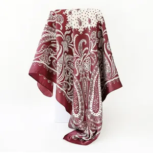 Detailed view of a red and cream paisley satin square scarf draping gracefully on display.
