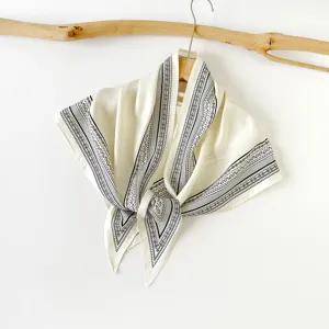 This detail view shows a chic black and white paisley silk triangle scarf, elegant for women.