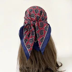 Detail view of a vintage red blue paisley printed square scarf worn on hair, 68cm stylish.