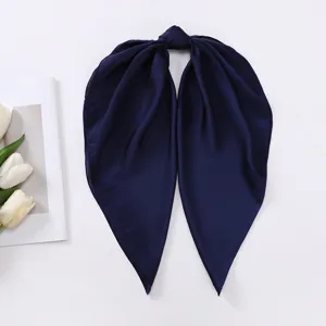 Dettaglio ravvicinato del foulard in seta satinata blu scuro con texture liscia e drappeggio.