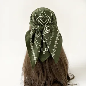 Close-up detail of dark green paisley square bandana scarf tied neatly on hair mannequin.