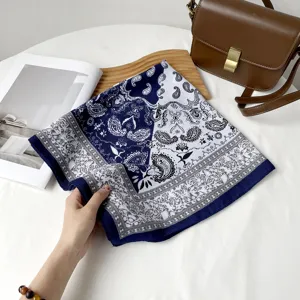 Detail view of a blue and white paisley patterned silk square scarf with elegant design.