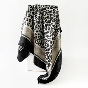 Detailed view of the luxury leopard print silk square scarf, showing smooth satin fabric and fine border.