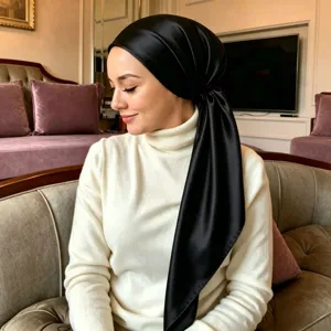 Detailed view of the sleek black satin hijab scarf worn elegantly in a daily indoor lifestyle setting.