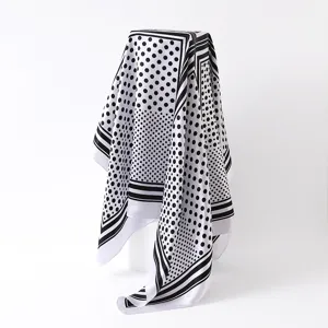 Gedetailleerd overzicht van de zwart-witte polkadot satijnen sjaal, toont drapering en print.