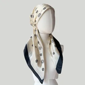 Detail view of the satin printed head wrap scarf, elegant floral pattern with black border.