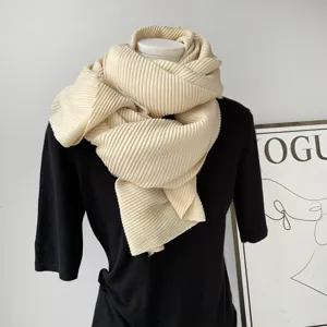 Close-up van een zachte beige geplooide sjaal elegant gedrapeerd op een paspop, winteraccessoire detail.
