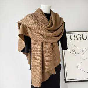 Detailopname van de elegante geplooide kameelkleurige sjaal gepresenteerd op een paspop.
