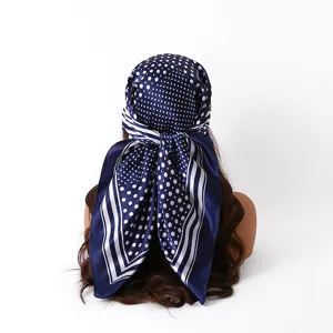 Gedetailleerd overzicht van een donkerblauwe polkadot satijnen sjaal op een pop.