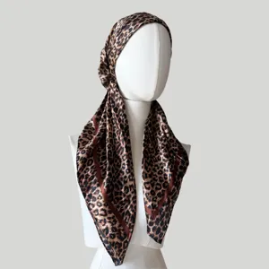 Detail shot of leopard print satin headscarf showing smooth fabric texture and classic pattern.