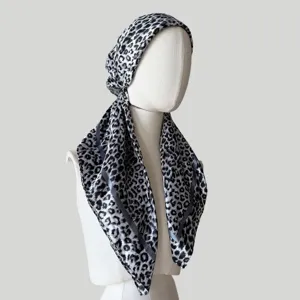 Detail view of the black and white leopard print satin head wrap cap showing smooth fabric texture.