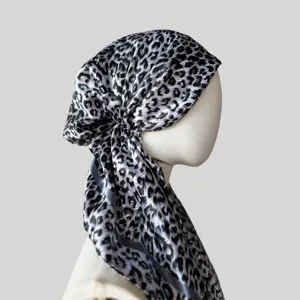 Close-up view of the black and white leopard print satin headscarf cap detail on mannequin display.