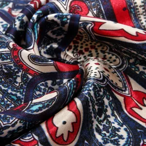 Detailed view of luxury paisley print silk satin square scarf, elegant red and blue design.