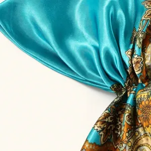 Turquoise silk satin headscarf detail showing paisley floral print fabric texture and fine gloss.