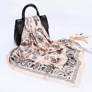Detailed view of a stylish paisley print square silk scarf draped elegantly on a black handbag.