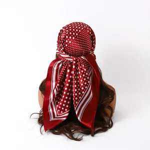 Gedetailleerd overzicht van rode satijnen sjaal met witte stippen, elegant haaraccessoire.