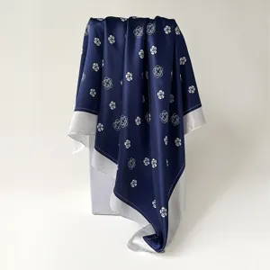 Detailed view of the dark blue silk scarf featuring elegant white camellia flower patterns.