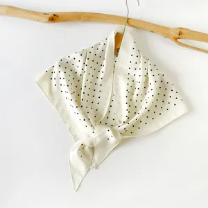 Elegant white silk scarf with black polka dots, chic triangle design for summer styling.