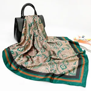 Detail view of a luxury paisley printed silk scarf, elegant green and brown square wrap.