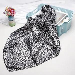 Detailed close-up of a chic black and white leopard print square satin silk scarf.