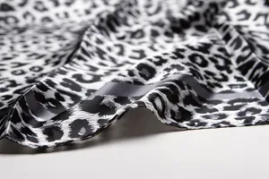 Black and white leopard print silk scarf detail view, elegant satin texture fabric close-up.