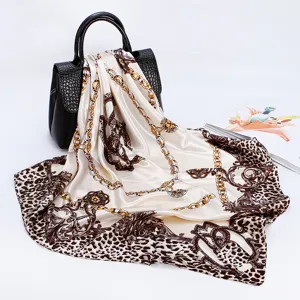 Detailed view of luxury brown leopard and golden chain print silk square scarf, smooth satin.