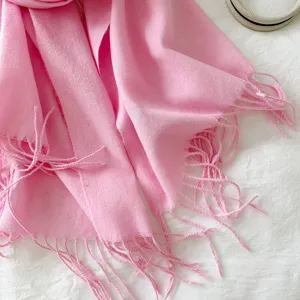 Close-up detail shot of soft pink cashmere-feel winter scarf with elegant tassel fringe.