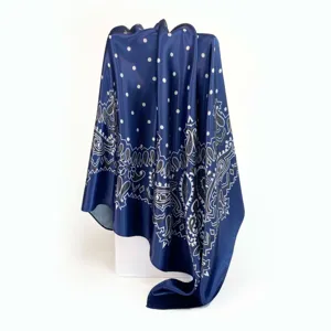 Detail view of the dark blue satin square scarf featuring white polka dots and paisley patterns.