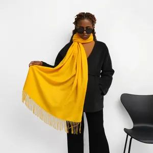 Close-up detail shot of a bright yellow imitation cashmere scarf with stylish fringe tassels.