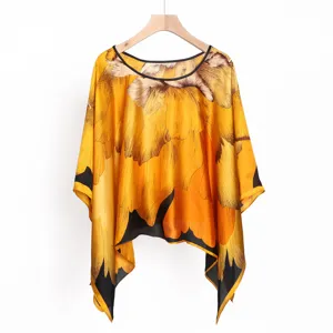 Detalle del chal poncho amarillo con estampado floral vintage, tela suave y dobladillo.