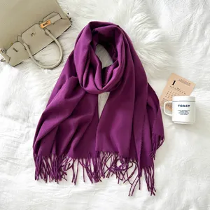 Detailed view of a soft purple imitation cashmere fringe scarf styled with luxury props on white.