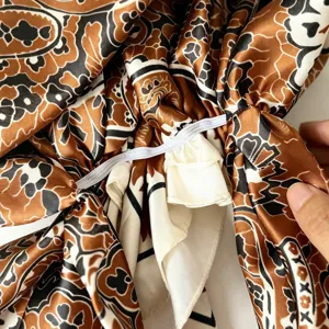 Detailansicht der braunen Paisley-Satin-Haube Stofftextur und des elastischen Bandes.