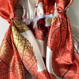 Detalle de pañuelo de satén con estampado de hojas, turbante floral de otoño elegante para mujer.