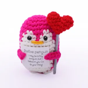 Handmade crochet positive penguin doll holding red heart and encouraging card, cute gift.