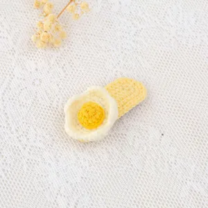Detailed close-up of handmade crochet fried egg hair clip showing fine yarn texture.