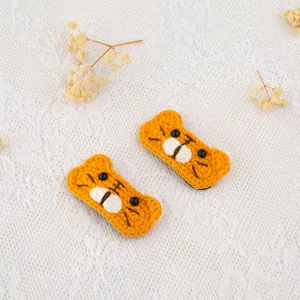 Close-up detail of cute handmade crochet orange tiger hair clips with lovely facial features.