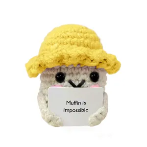 Dettaglio bambola muffin all'uncinetto, peluche carino con cappello giallo e cartello.