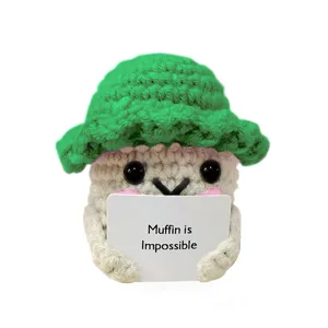 Vista dettagliata di peluche muffin all'uncinetto fatto a mano con cappellino verde e frase.