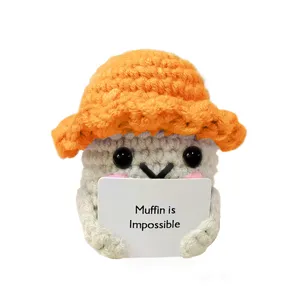 Bambola muffin all'uncinetto fatta a mano con cappello arancione e carta positiva.