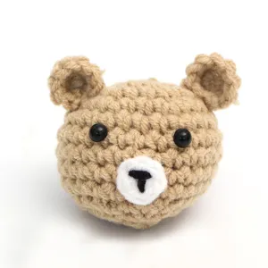 Close-up detail of a handmade crochet bear head pendant showing fine wool knit texture.