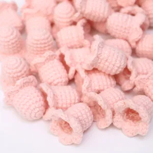 Handmade crochet lily of the valley flower head detail, pink knit DIY craft accessory.