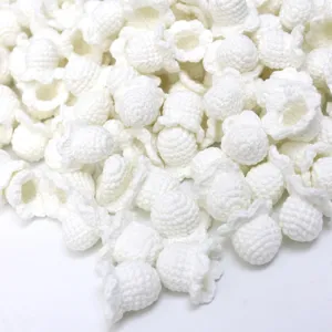 Detailed close-up of handmade white crochet lily of the valley flower heads, wool knit craft accessories.