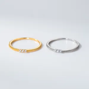 Detail von minimalistischen Silber- und Goldringen mit drei Diamanten und Perlrändern.