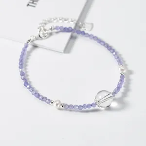 Detailopname van paarse kristalen en parel armband met zilveren elementen, elegant ontwerp.