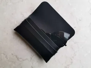 Tragbares schwarzes Leder-Faltbrillenetui mit Sonnenbrille, schlichtes Design, langlebiger Schutz.