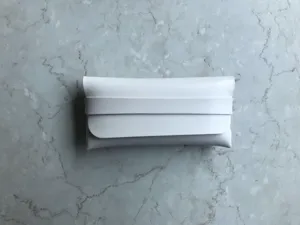 Detailaufnahme eines minimalistischen weißen Lederetuis für Sonnenbrillen auf Marmor.