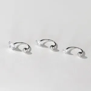 Detailansicht von drei silbernen Hufeisen-Piercing-Ohrringen mit funkelnden Zirkonia und Kugel.