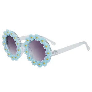 Occhiali da sole rotondi per bambini con margherite azzurre e aste trasparenti molto eleganti.